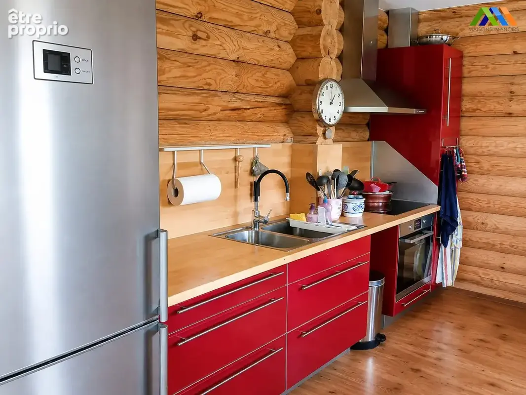 Modern fitted kitchen with red cabinetry, wood worktops and natural timber walls.