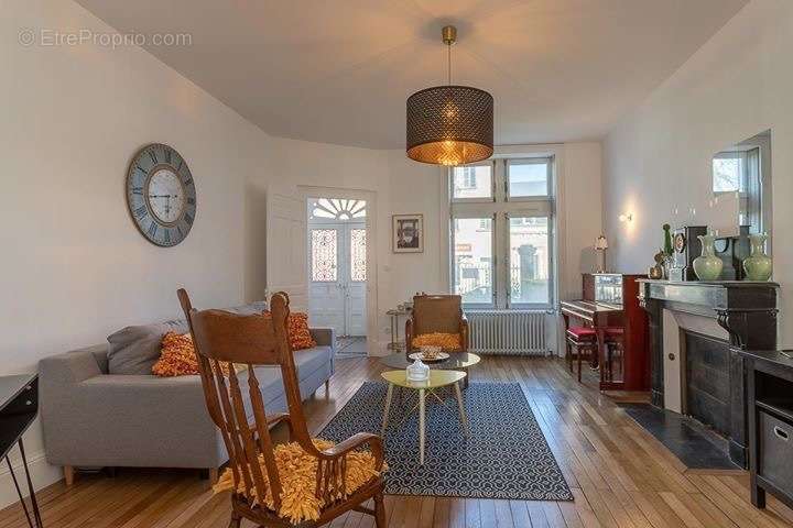 Salon de 23 m2 avec parquet et cheminée en marbre et belle hauteur sous plafond.