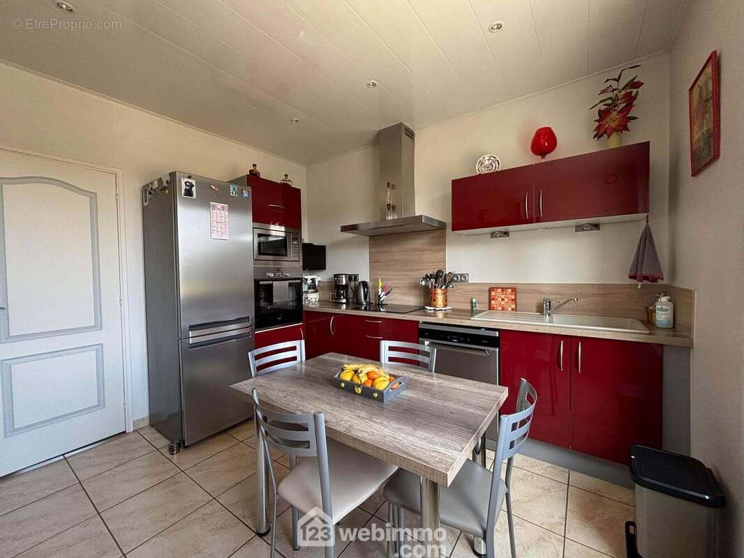 Attenante au séjour, la cuisine aménagée et équipée de 10 m2 dispose d'un escalier pour accéder au niveau inférieur et au jardin. - Maison à DANGE-SAINT-ROMAIN