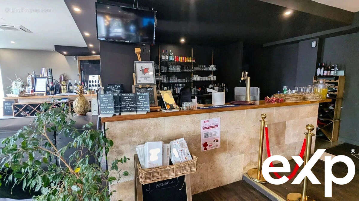 Un bar moderne avec un comptoir en bois, des étagères de bouteilles, et une plante verte. - Autre à AGEN