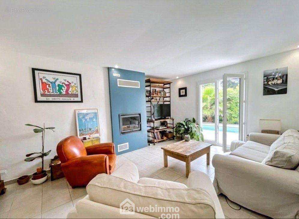 Espace salon cocooning avec cheminée insert, baigné de lumière et ouvert sur la piscine. - Maison à SAINTE-MAXIME