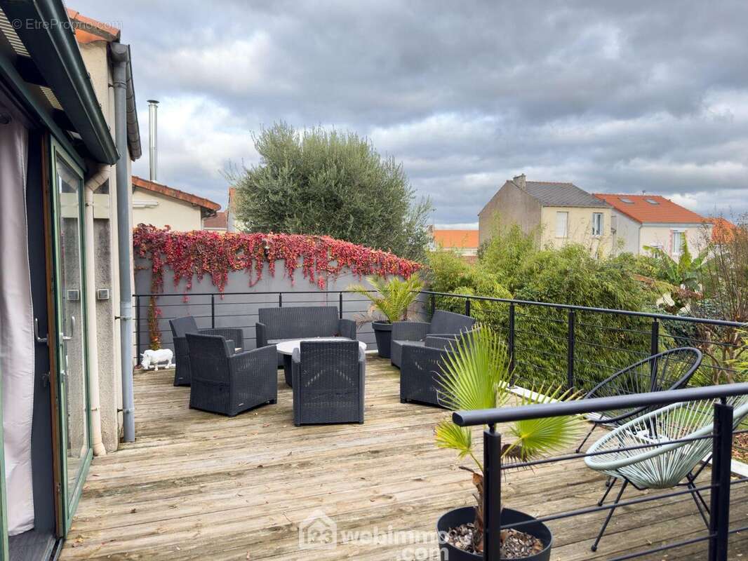 A l'extérieur, une terrasse bois domine la parcelle. - Maison à CHOLET