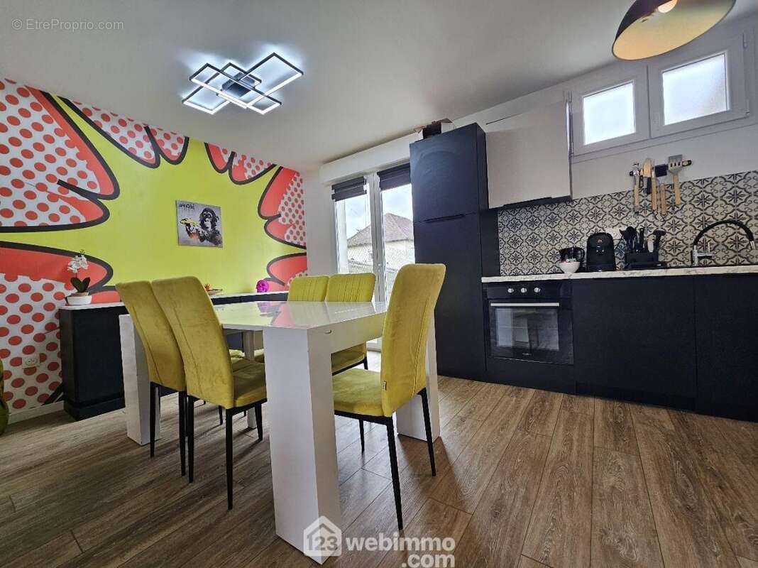 Un espace repas moderne et coloré, ouvert sur la cuisine pour des moments conviviaux au quotidien - Maison à TINQUEUX