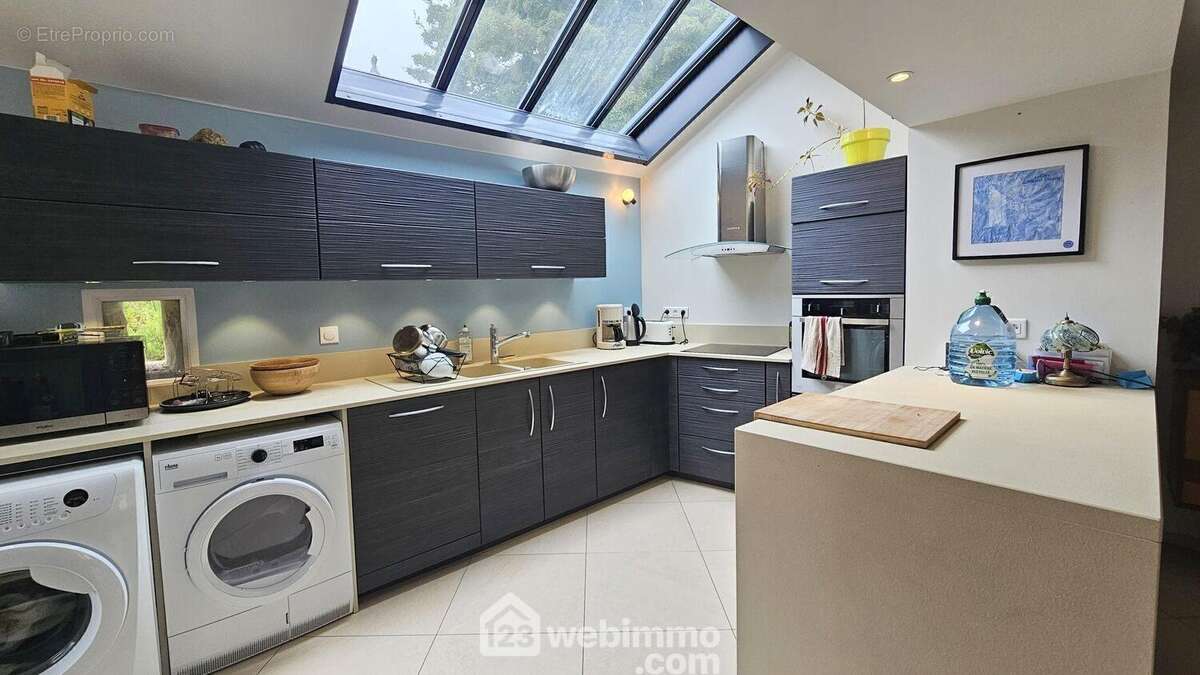 Une cuisine ouverte entièrement aménagée et équipée avec accès direct sur la terrasse. - Maison à CELY