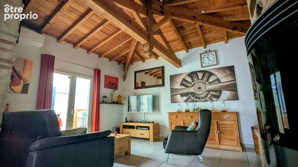 Un salon avec un plafond en bois, des meubles modernes, et des oeuvres d'art murales.