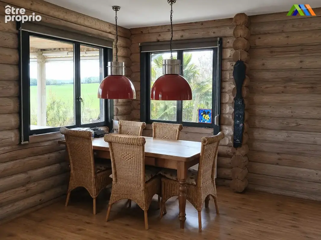 Dining area with wicker chairs, timber walls and views over the garden.