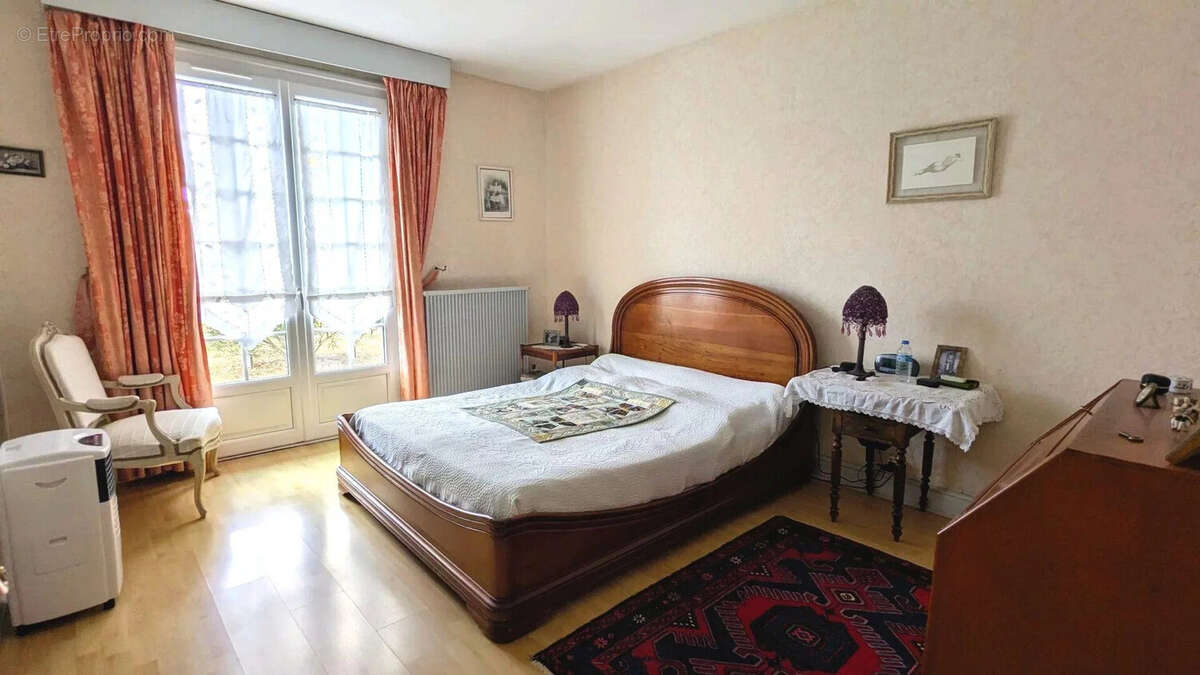 Une chambre avec un grand lit, des rideaux roses, un tapis coloré et des meubles en bois. - Maison à FOULAYRONNES