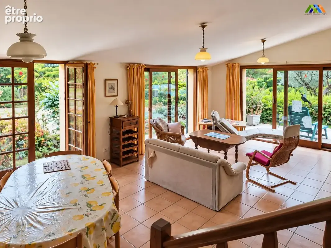 Garden-facing living and dining room  with broad glazed openings and tiled flooring.