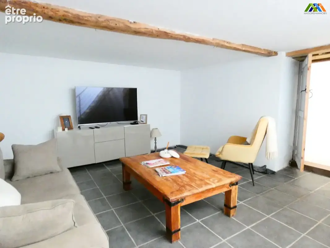 Salon confortable avec poutre apparente et ambiance détendue.