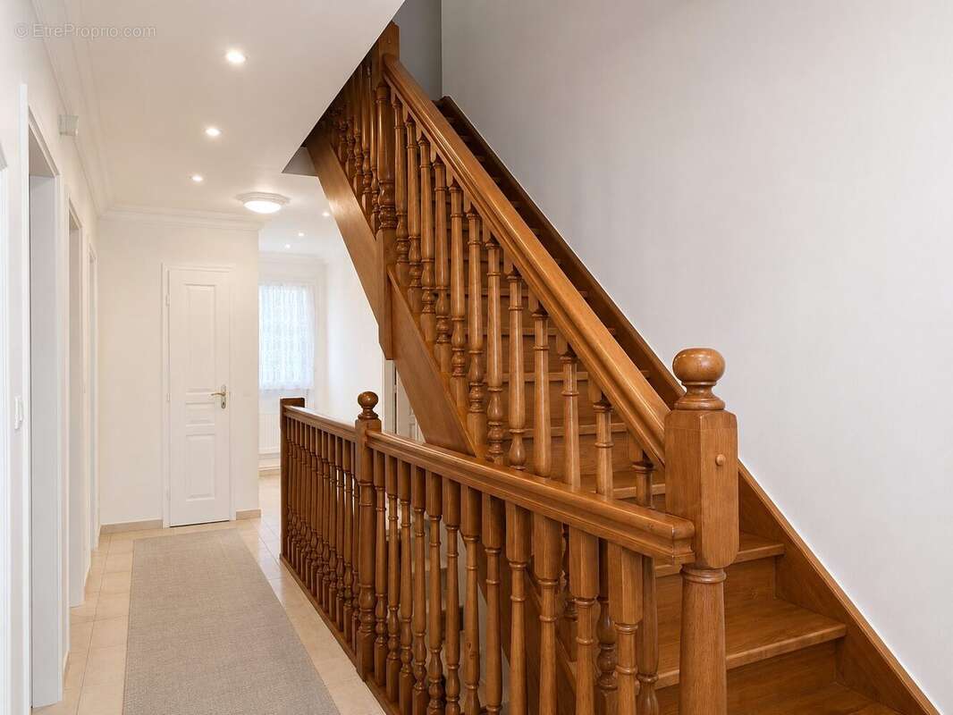 Escalier en bois massif desservant les différents niveaux de la maison avec des espaces de circulation spacieux et lumineux. - Maison à VAL-DE-REUIL