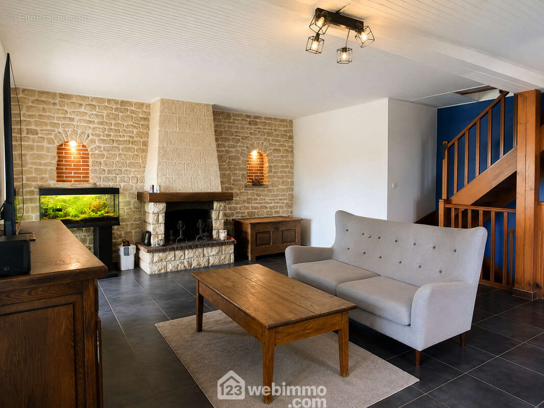 Séjour traversant offrant de beaux volumes, une cheminée en pierre et un espace convivial.