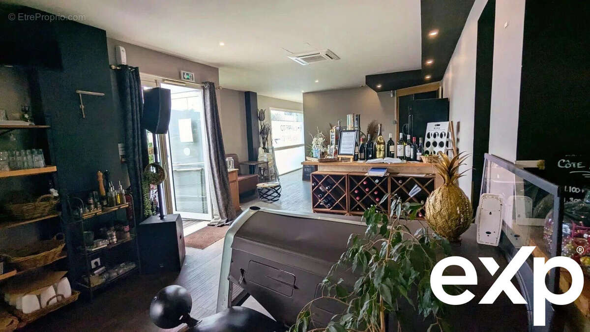 Un intérieur de bar ou restaurant avec des étagères de boissons, un comptoir à vin, et une plante décorative près de l'entrée. - Autre à AGEN