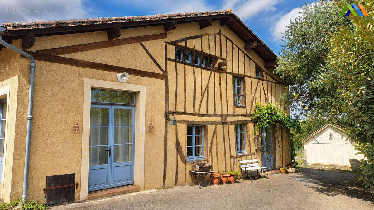Maison de caractère avec façade à colombages, porte bleue et jardin devant la maison.