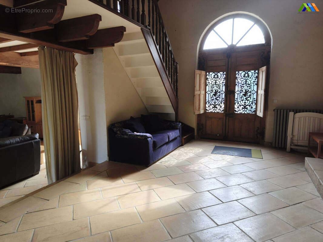 Elegant reception hall with exposed beams, traditional tiled floor and a striking arched window.