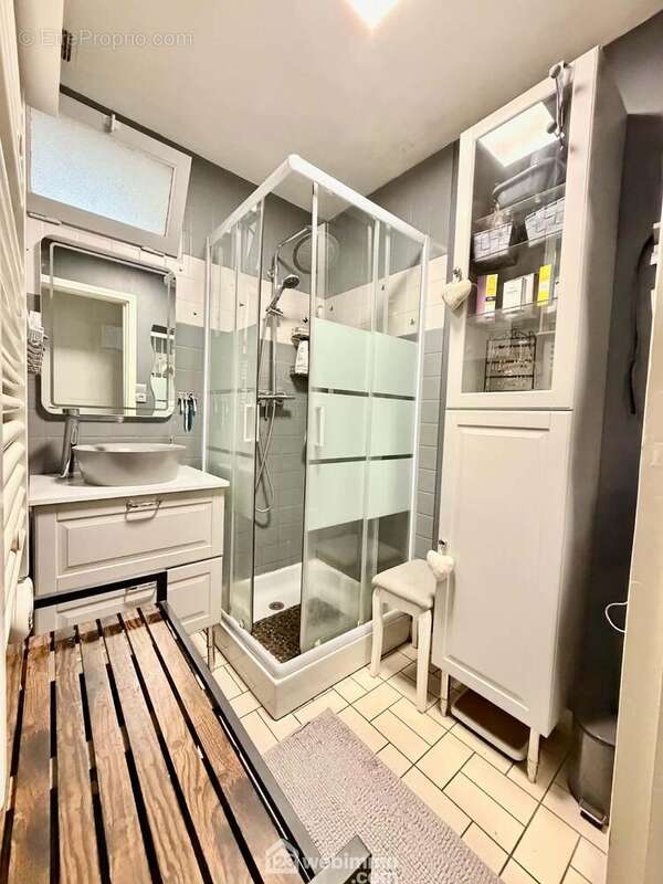 La salle de bain équipée d'une douche, un vasque et d'un sèche serviettes