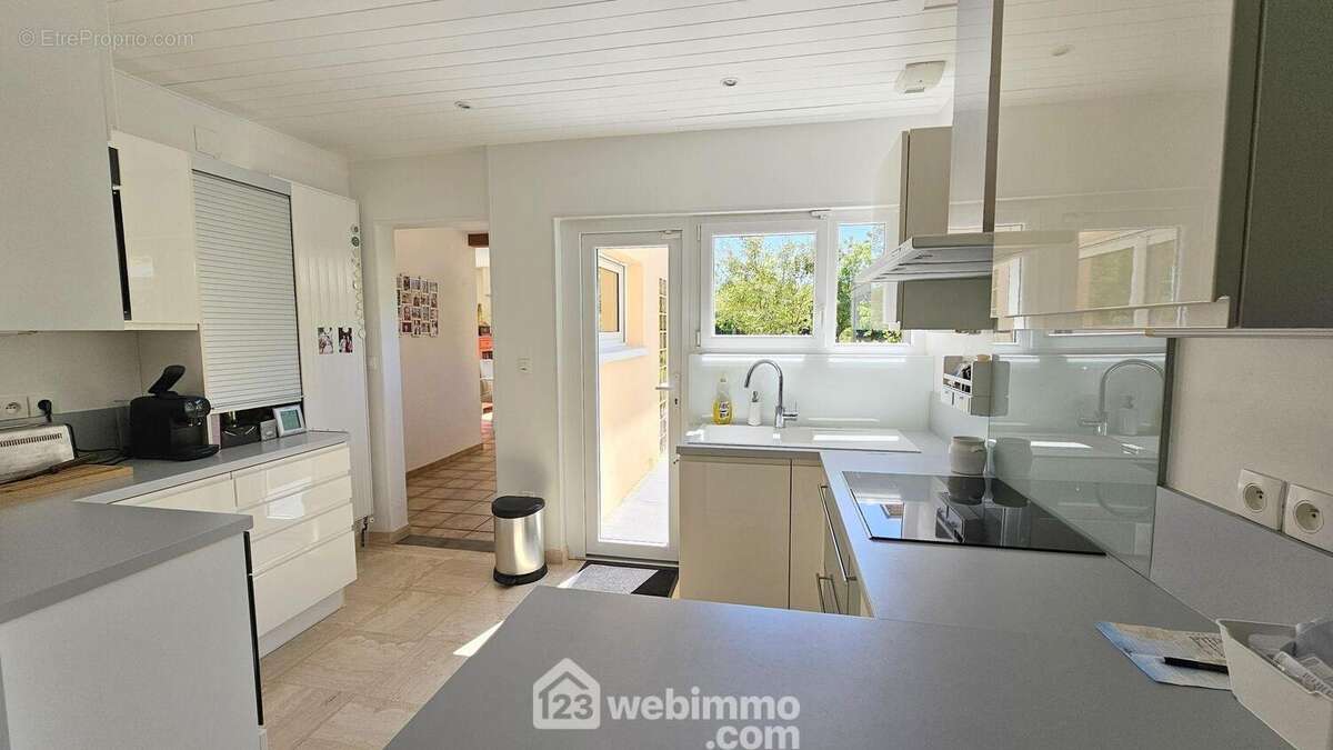 Une cuisine toute équipée et fonctionnelle avec un accès sur une terrasse. - Maison à BARBIZON