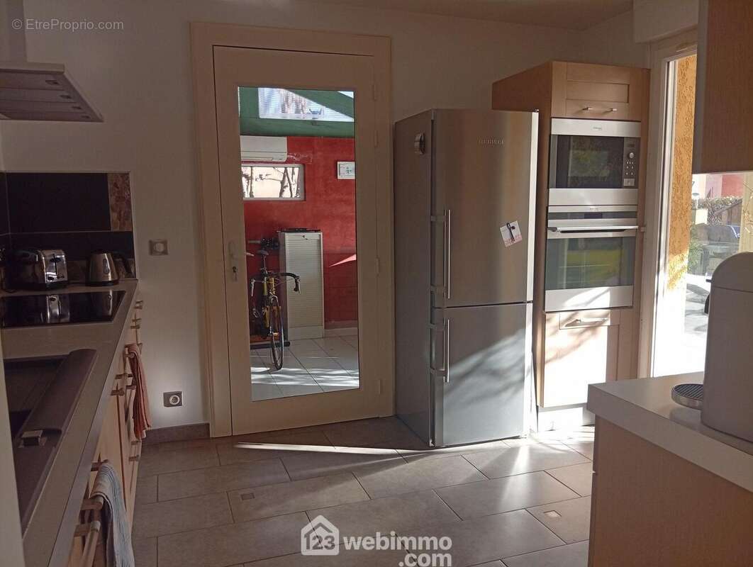 Cuisine toute aménagée et offrant accès à terrasse, traversante elle s'ouvre vers la pièce du SPA - Maison à LE THORONET