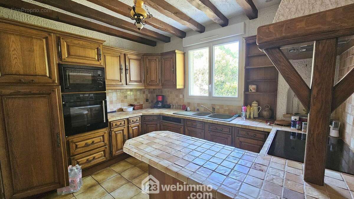 Une cuisine équipée de 11 m² avec un accès à la buanderie. - Maison à MILLY-LA-FORET