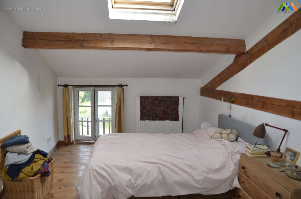 Bright bedroom with exposed beams, wooden floor and traditional character in a village house.