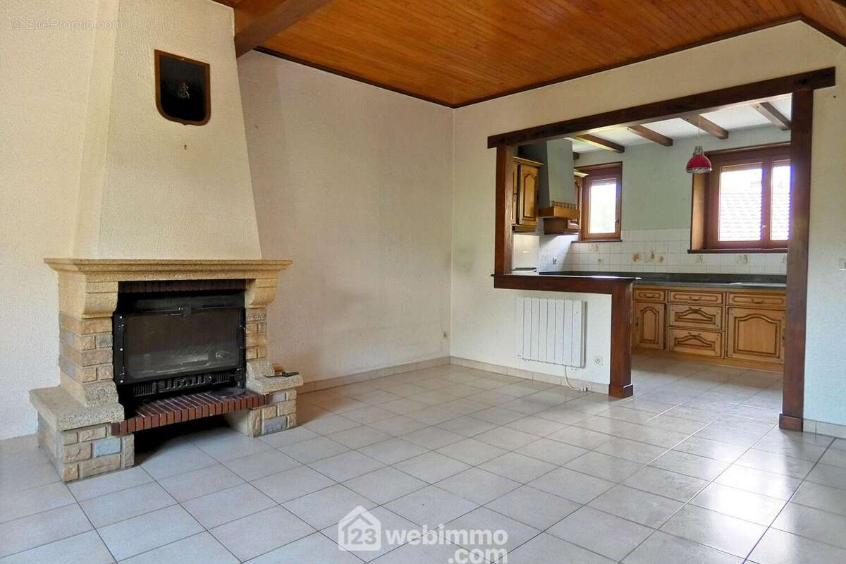 ... à la chaleureuse pièce de vie agrémentée d'une cheminée qui apporte charme et convivialité - Maison à UGINE