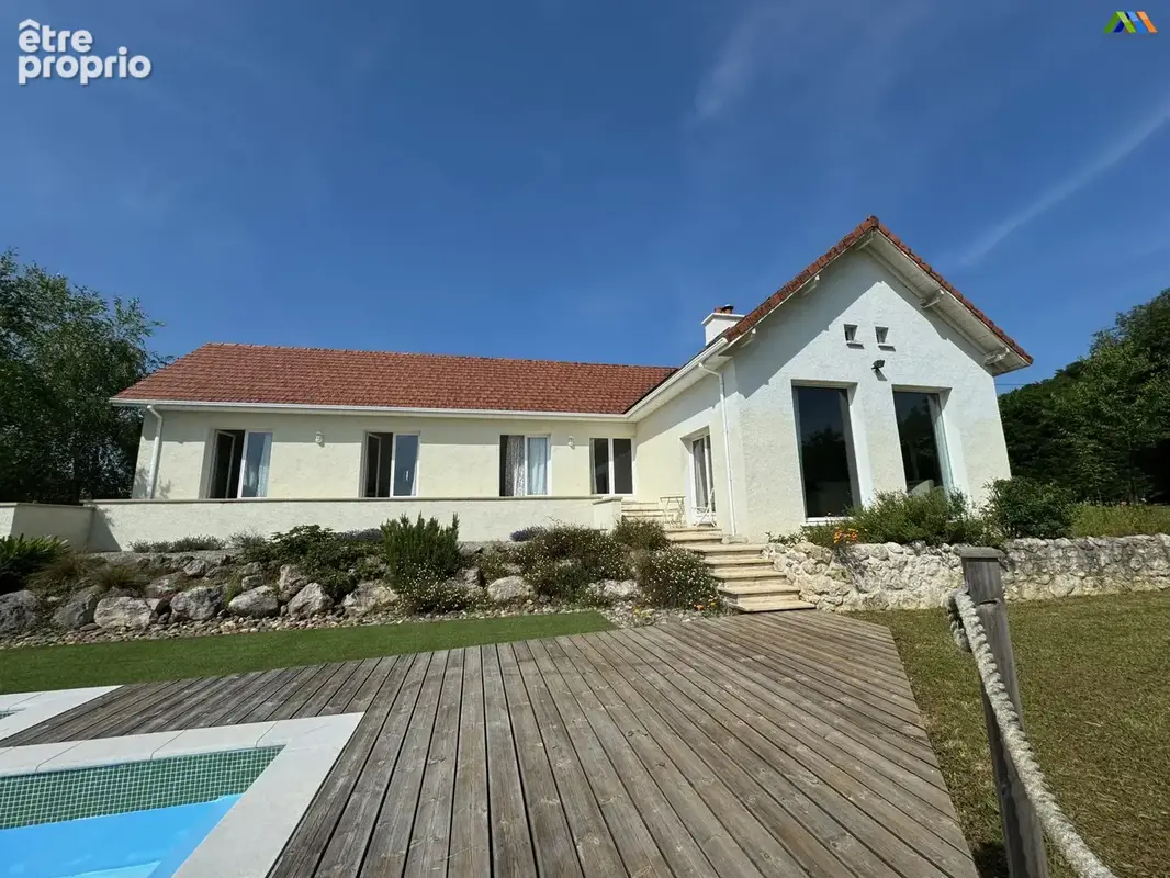 Maison en Gascogne avec grande terrasse en bois, piscine et façade claire sous un ciel bleu. - Maison à GARLIN