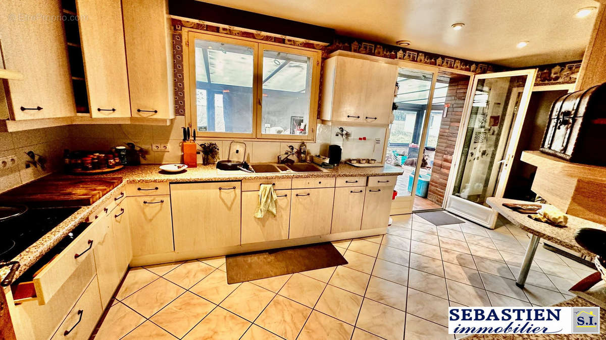 Cuisine aménagée donnant dans véranda - Maison à LES BORDES-AUMONT