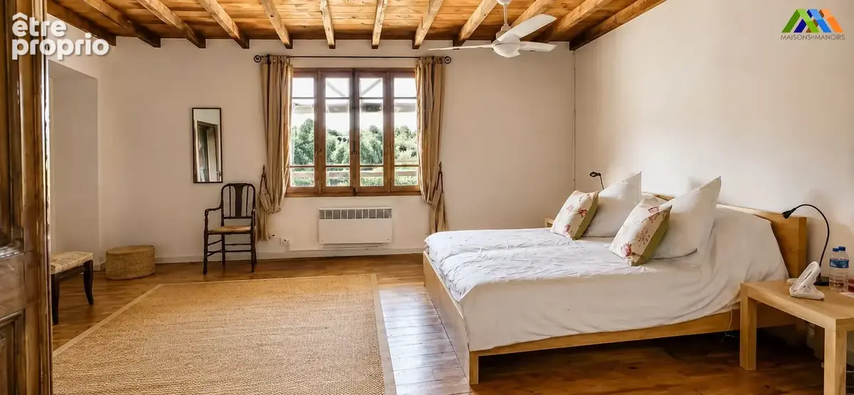 Chambre lumineuse avec poutres et plancher en bois.