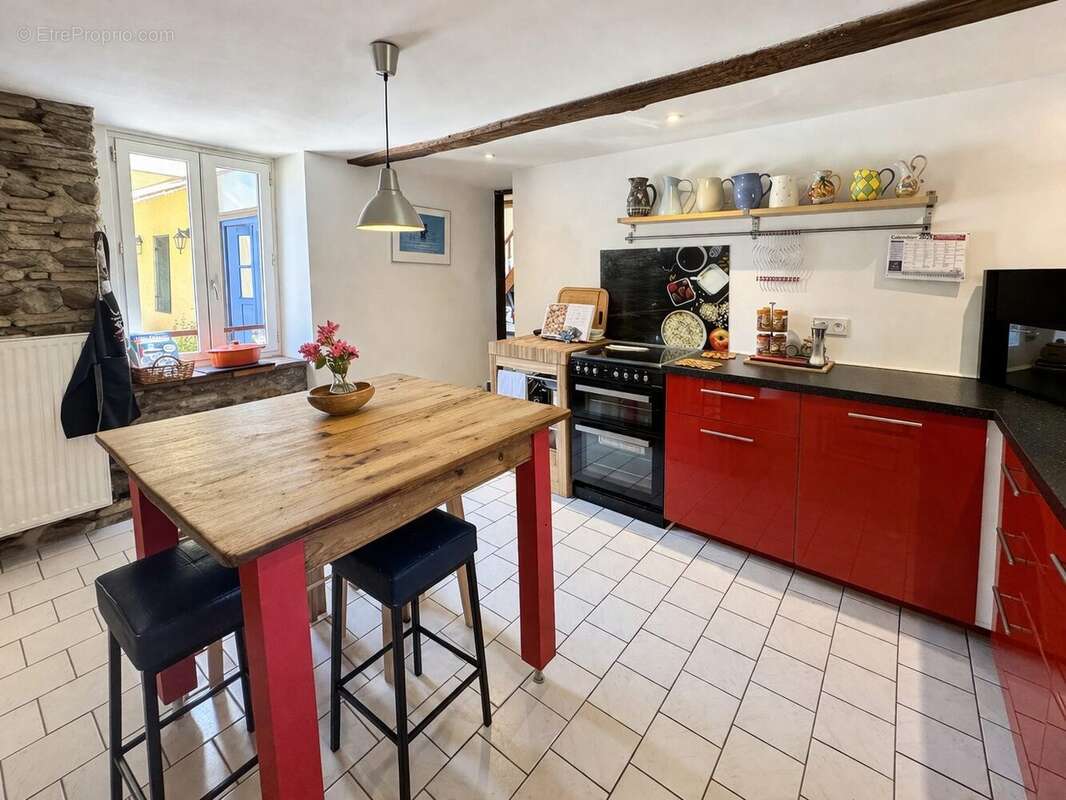 Cuisine équipée lumineuse avec coin repas et poutres apparentes - Maison à TRIE-SUR-BAISE