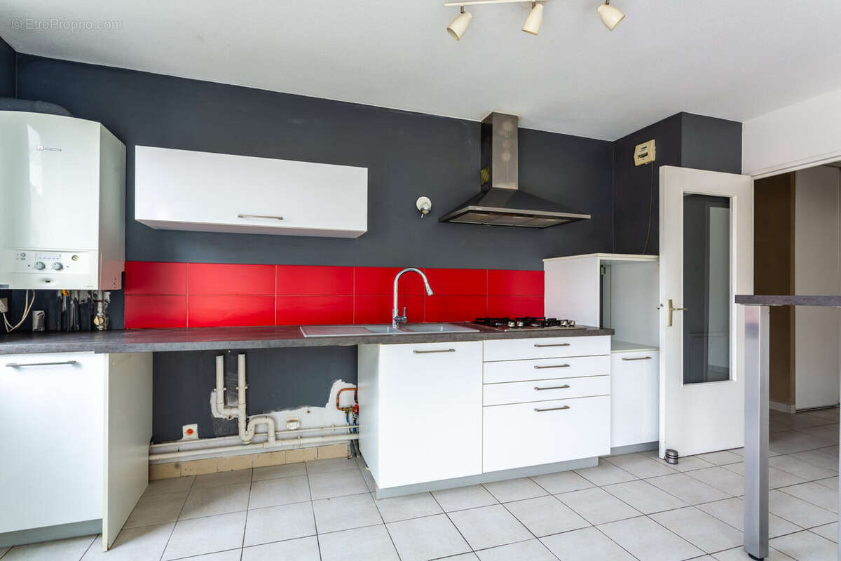 Cuisine équipée rouge et blanche, fonctionnelle, ouverte sur la pièce de vie. - Appartement à FRANCHEVILLE