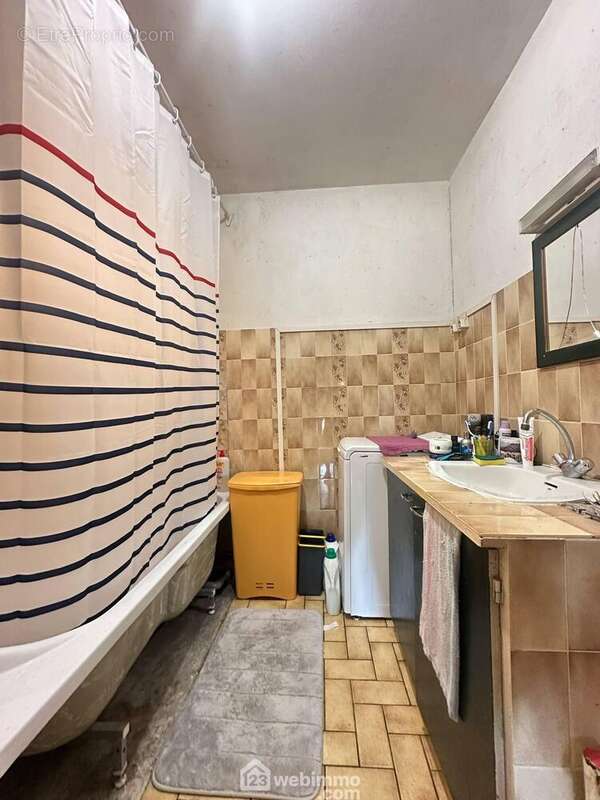La salle de bains avec vasque sur meuble et une baignoire
