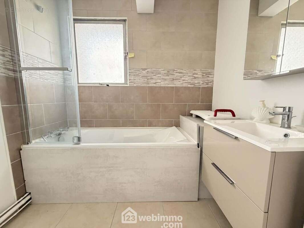 La salle de bains avec vasque sur meuble et une baignoire/douche - Appartement à LAON