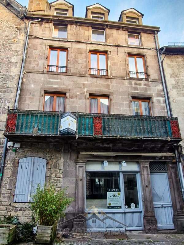 façade en pierre de taille avec vitrine sur rue commerçante - Appartement à BESSE-ET-SAINT-ANASTAISE