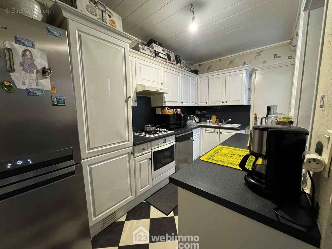 Une cuisine équipée avec hotte, plaque et four - Appartement à SAINT-QUENTIN
