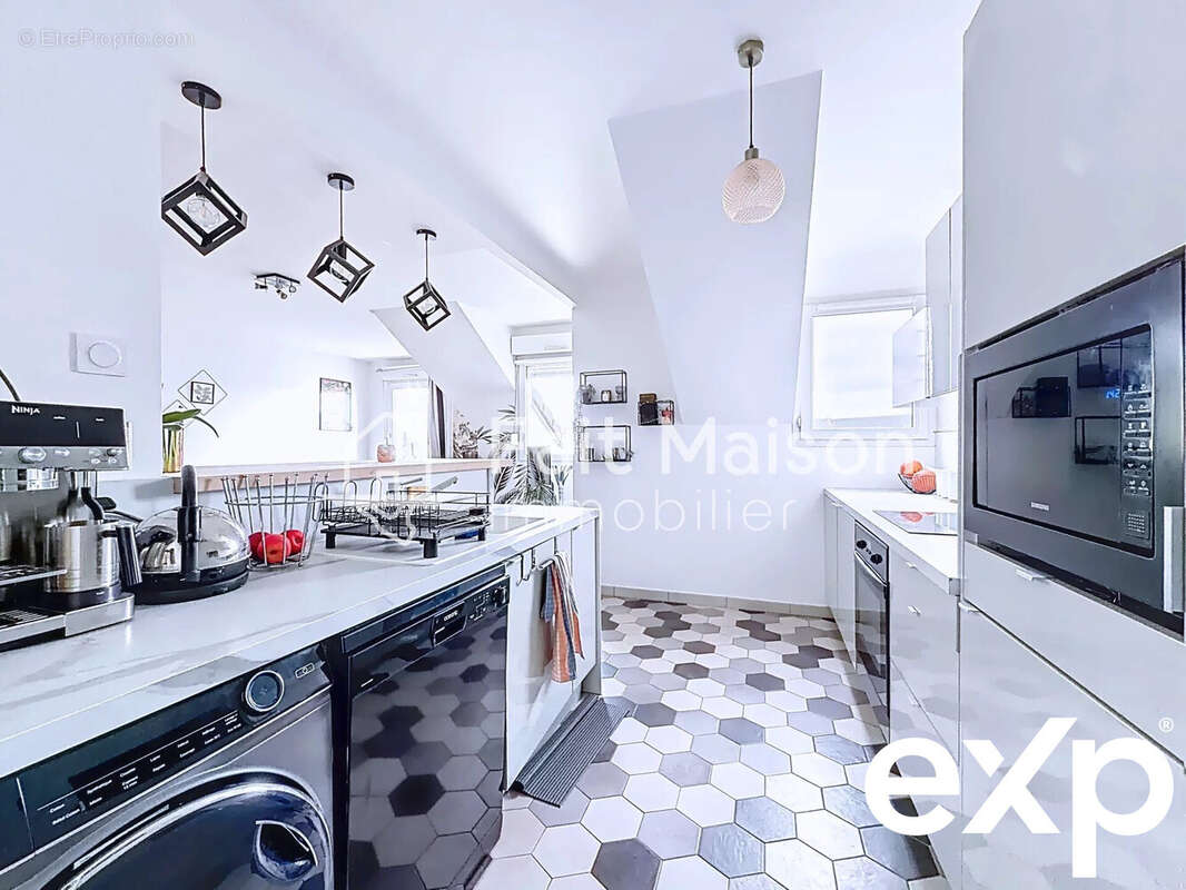 Cuisine moderne avec carrelage hexagonal, électroménagers en acier inoxydable et luminaires suspendus. - Appartement à MASSY