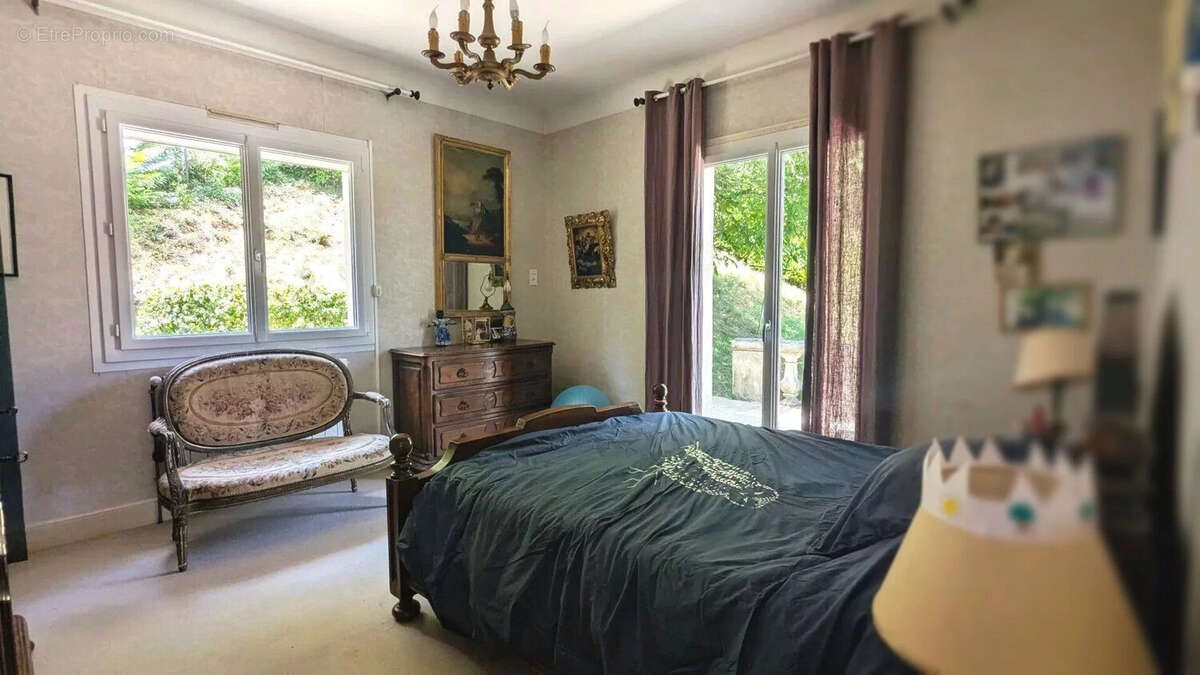 Une chambre confortable avec un lit, des rideaux violets, un canapé et des décorations murales. - Maison à FOULAYRONNES
