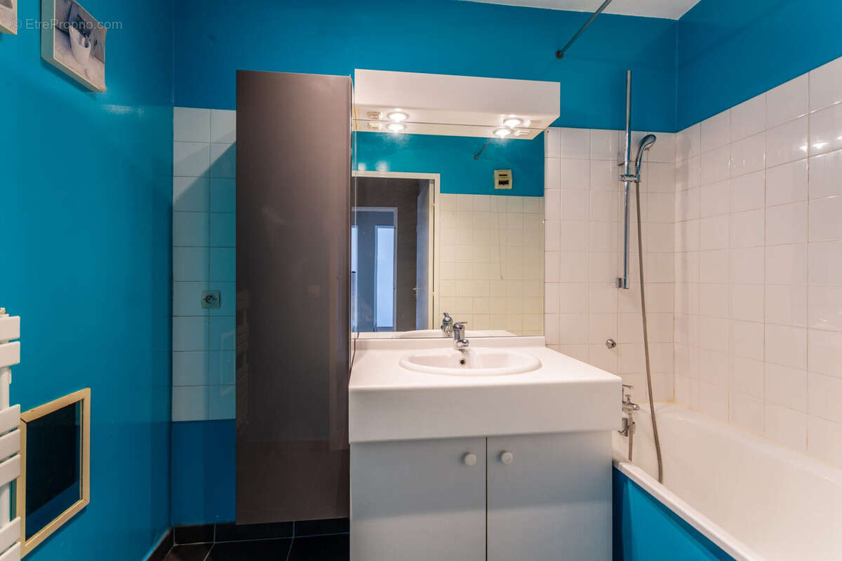 Salle de bain avec baignoire, meuble vasque et rangements, bon état. - Appartement à FRANCHEVILLE