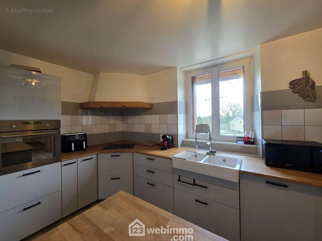 Voici la cuisine aménagée et fonctionnelle, offrant un espace agréable pour cuisiner au quotidien. - Maison à REVILLON