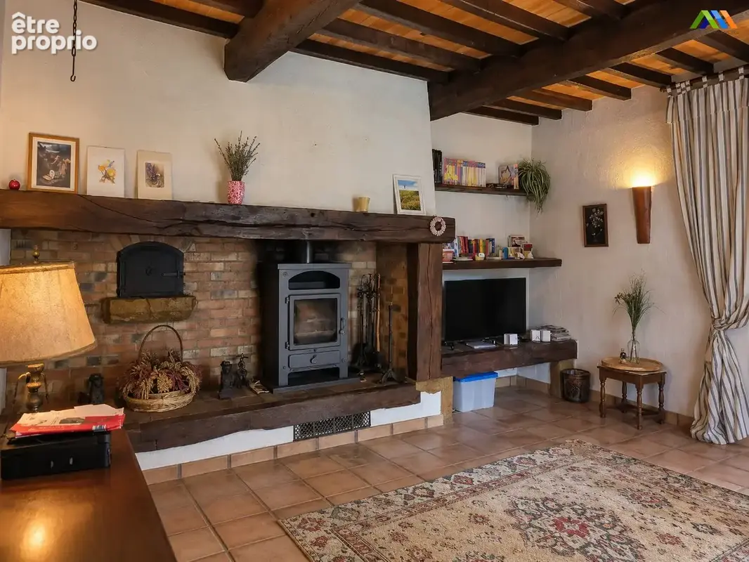 A stove sits within a brick fireplace framed by a substantial timber mantel.