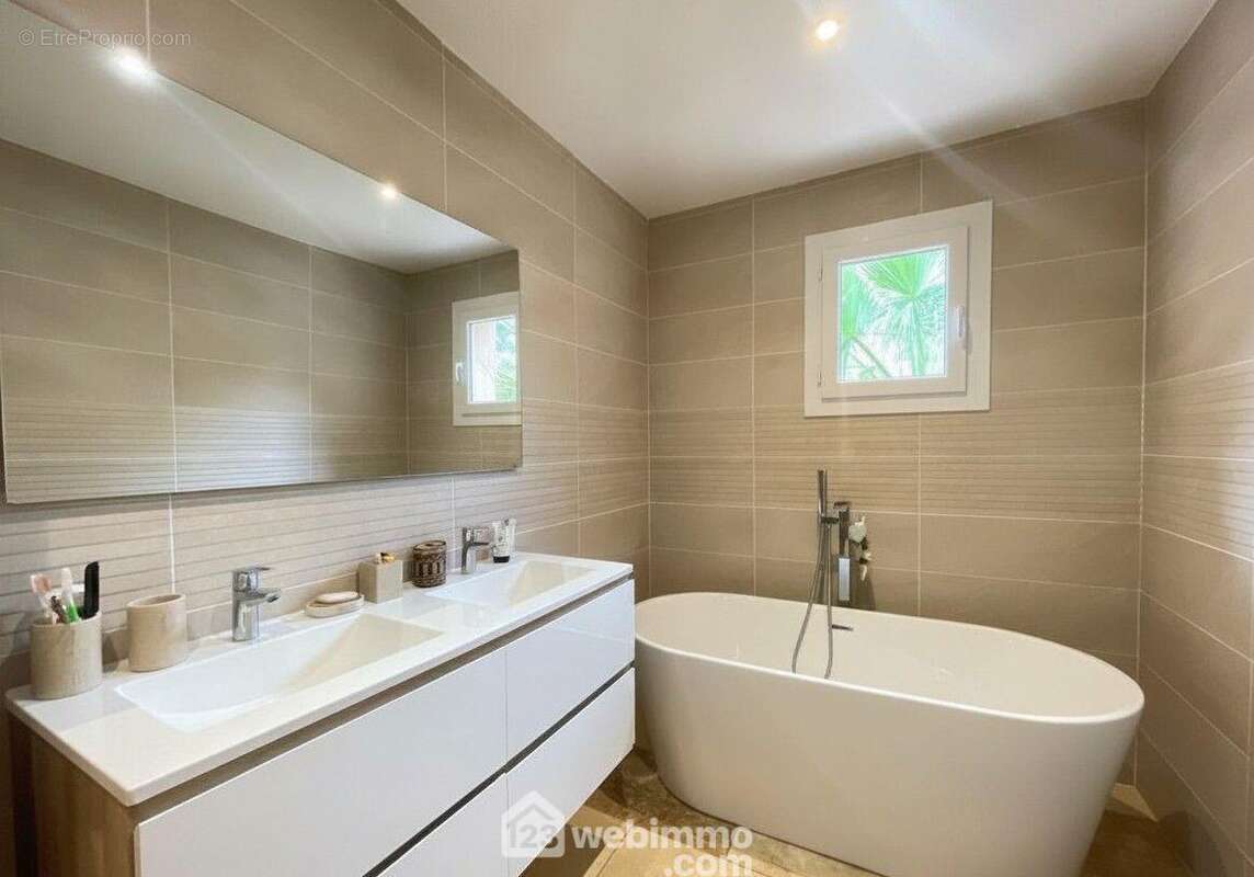 Une salle de bains spacieuse, équipée d'une baignoire et d'une double vasque avec espace douche.