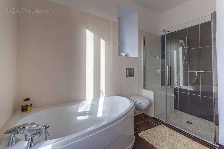 Salle de bain de 9 m2 avec baignoire, douche à l'italienne, double vasque et WC.
