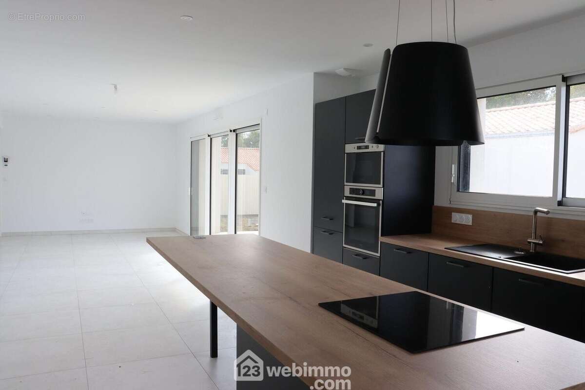 Cuisine équipée ouverte sur une large pièce de vie. - Maison à SAINT-HILAIRE-LA-FORET