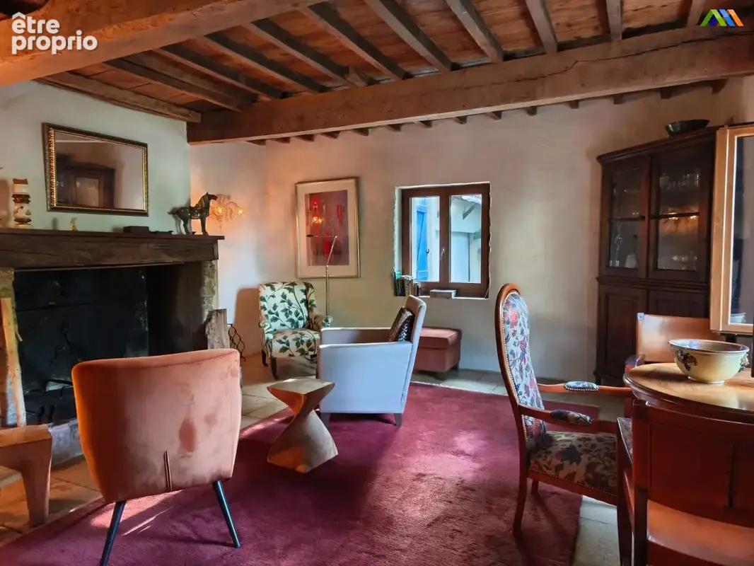 Salon chaleureux avec cheminée, poutres apparentes et beaux éléments anciens