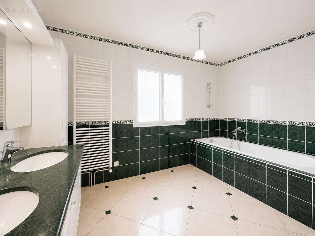 Grande salle de bains familiale avec baignoire, double vasque et finitions soignées dans un style moderne et intemporel. - Maison à VAL-DE-REUIL