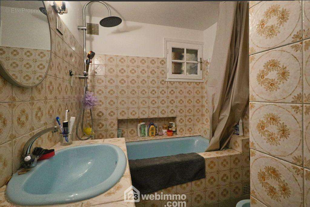Depuis la cuisine, une salle de bains à rafraîchir, un WC et une buanderie.