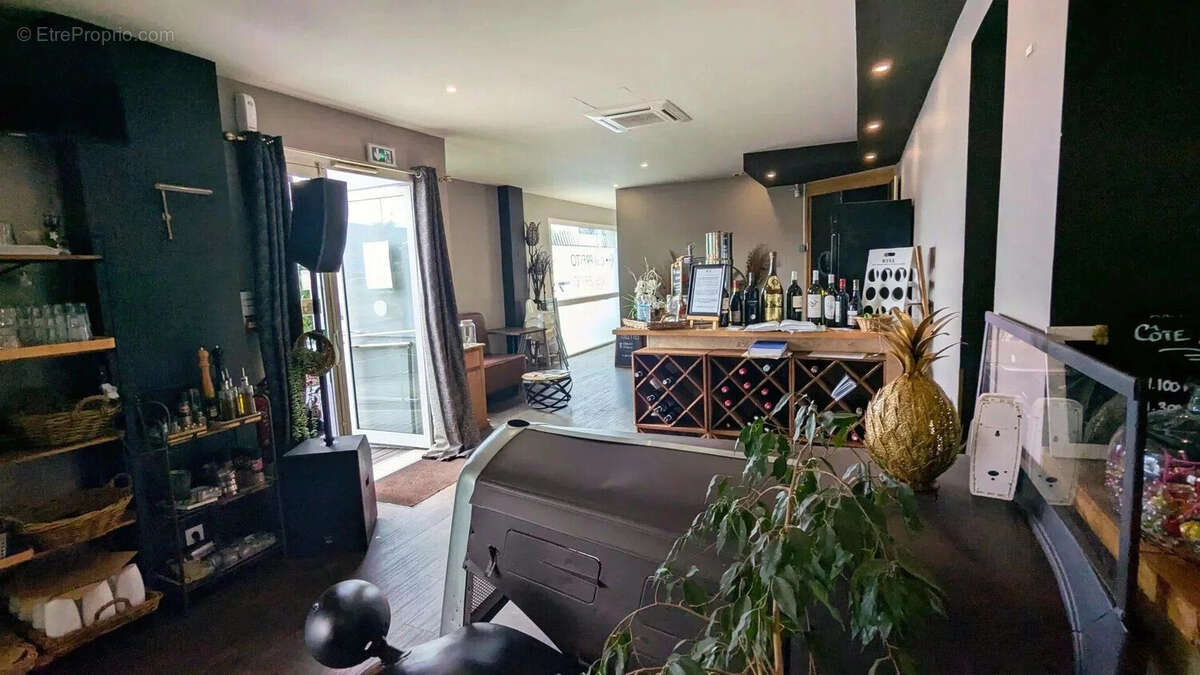Un intérieur de bar ou restaurant avec des étagères de boissons, un comptoir à vin, et une plante décorative près de l'entrée. - Autre à AGEN