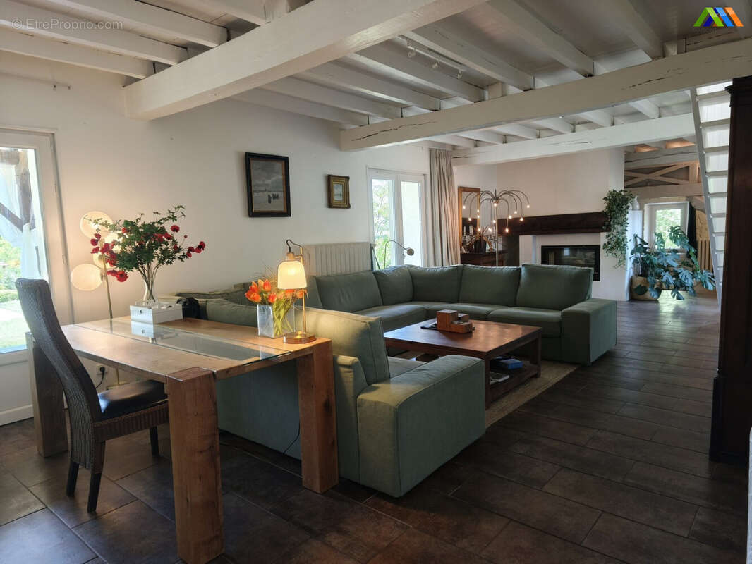 Bright open-plan reception room with fireplace and exposed beams.