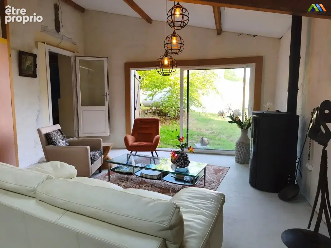 Séjour lumineux ouvert sur le jardin, avec poêle à bois et vue sur la campagne