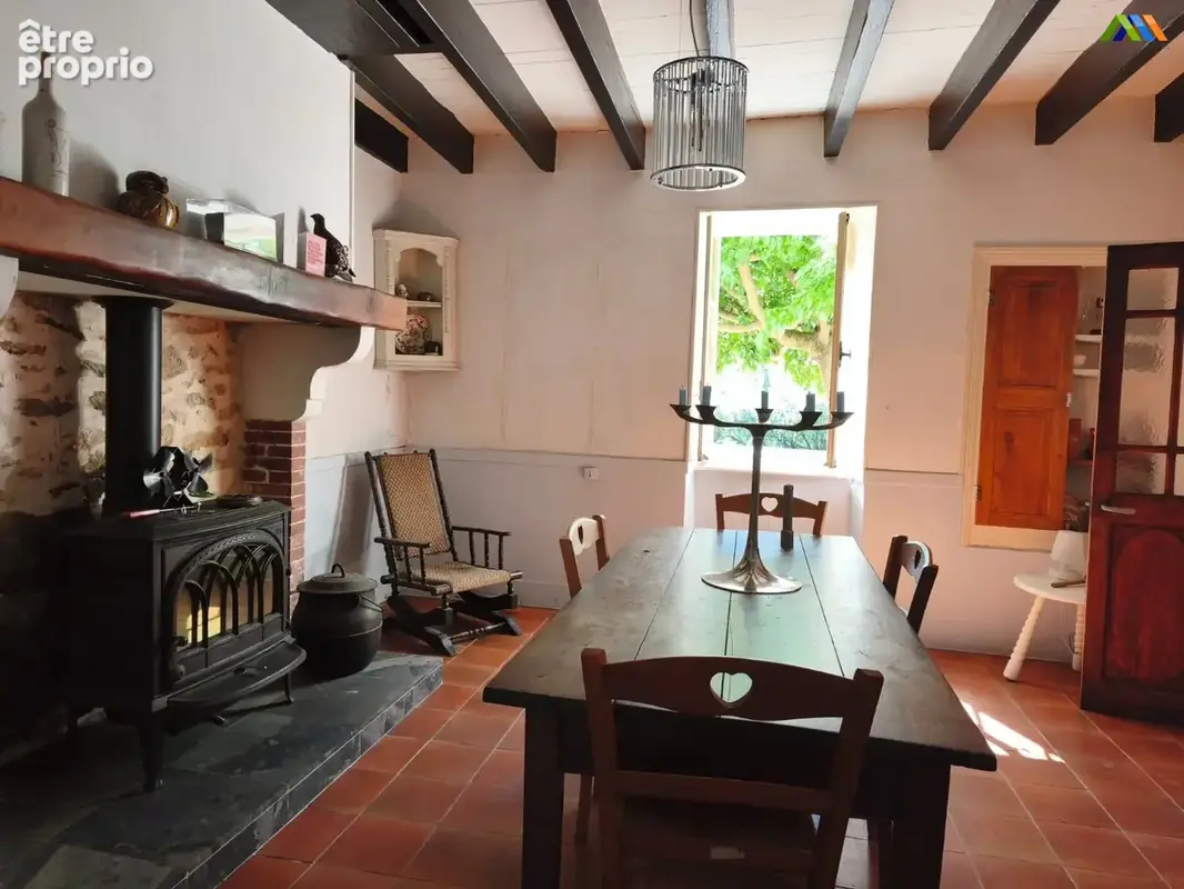 Characterful dining room with exposed beams, a traditional fireplace and terracotta flooring.