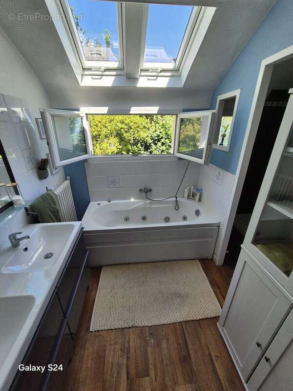 Salle de bains fonctionnelle avec baignoire, bénéficiant d'une belle luminosité naturelle. - Maison à LAVAL