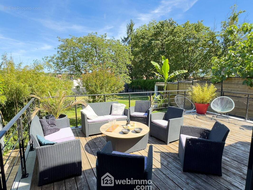 A l'extérieur, une terrasse bois domine la parcelle. - Maison à CHOLET